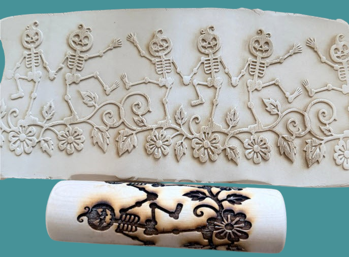 Sharon Hoppe Designs 7-inch wooden rolling pin with dancing skeleton and pumpkin pattern embossed on clay surface.